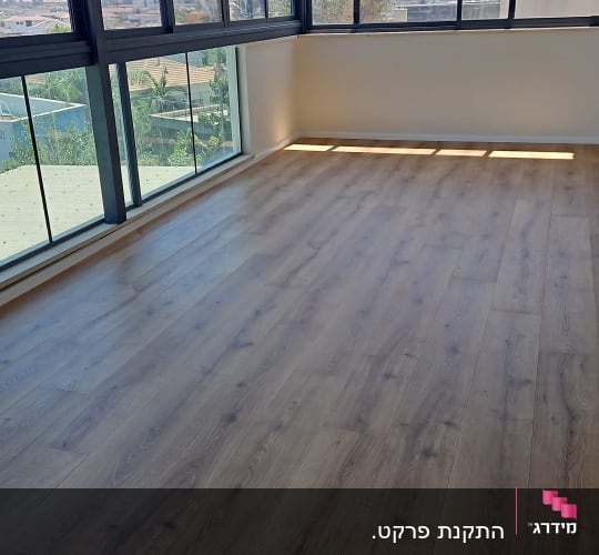 רצפת פרקט בחדר עם חלונות גדולים